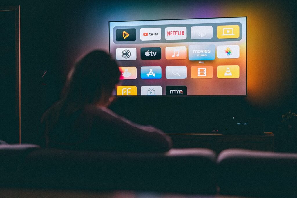 TV with applications in front of a person sitting on a couch in a dark room
